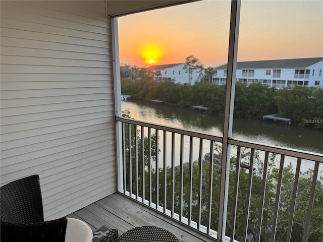 balcony at dusk featuring a water view