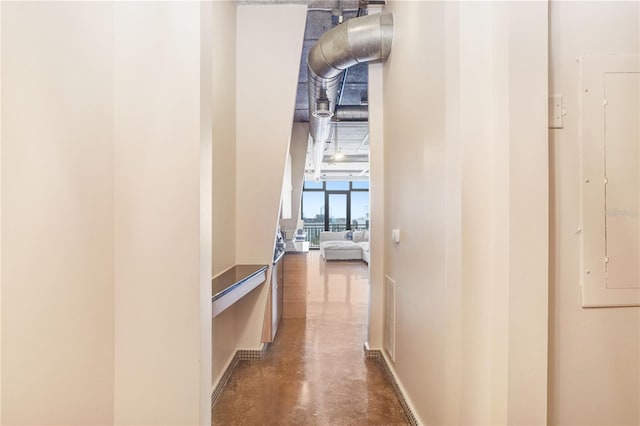 hallway featuring concrete flooring, visible vents, and electric panel