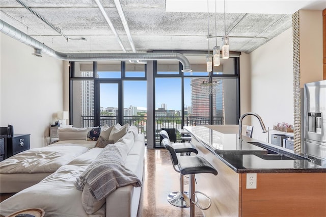 bedroom featuring a sink, stainless steel fridge with ice dispenser, a view of city, a wall of windows, and finished concrete floors