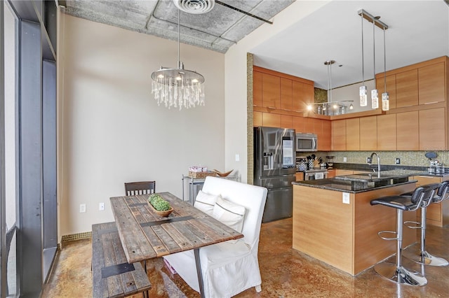 kitchen featuring a kitchen island with sink, a notable chandelier, stainless steel appliances, visible vents, and decorative backsplash