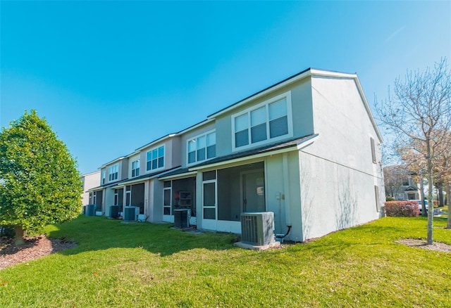 back of property with a lawn, cooling unit, a sunroom, and stucco siding