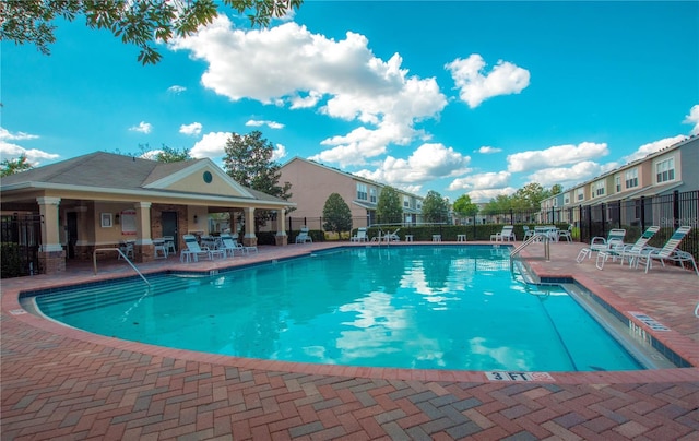 community pool with a patio area and fence