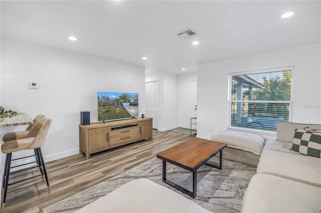 living area with baseboards, light wood-type flooring, visible vents, and recessed lighting