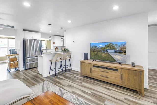 living room with baseboards, wood finished floors, and recessed lighting