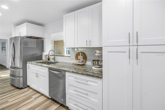 kitchen featuring appliances with stainless steel finishes, stone counters, a sink, and backsplash