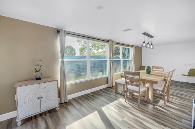 dining area with wood finished floors, visible vents, and baseboards