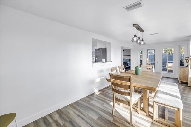 dining room with french doors, wood finished floors, visible vents, and baseboards