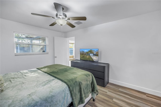 bedroom featuring baseboards, visible vents, ceiling fan, and light wood finished floors