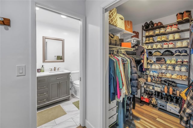 walk in closet featuring marble finish floor and a sink