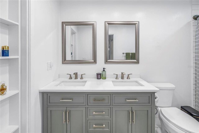 bathroom featuring toilet, double vanity, and a sink