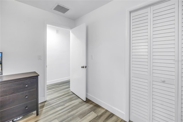 bedroom featuring light wood finished floors, visible vents, and baseboards