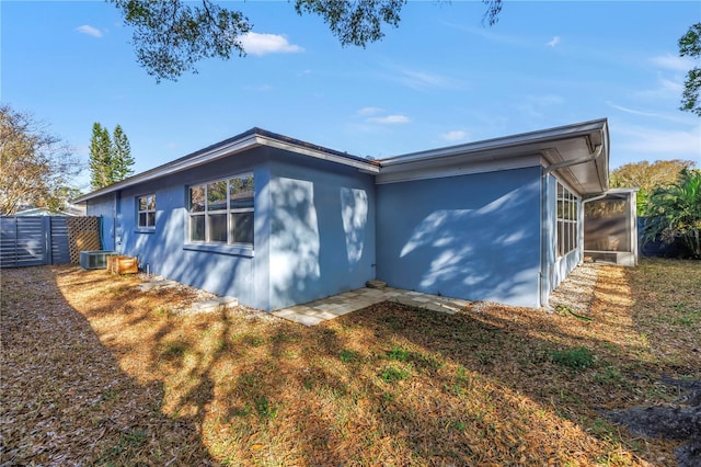 view of home's exterior with a sunroom and fence