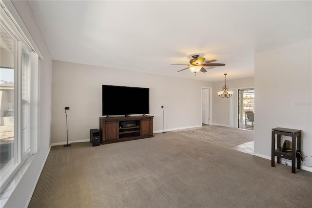 unfurnished living room featuring light carpet, ceiling fan with notable chandelier, and baseboards