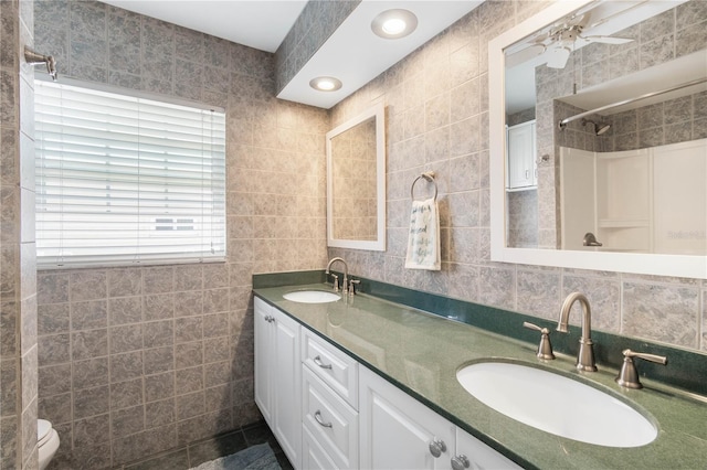 bathroom featuring tile walls, a shower, double vanity, and a sink