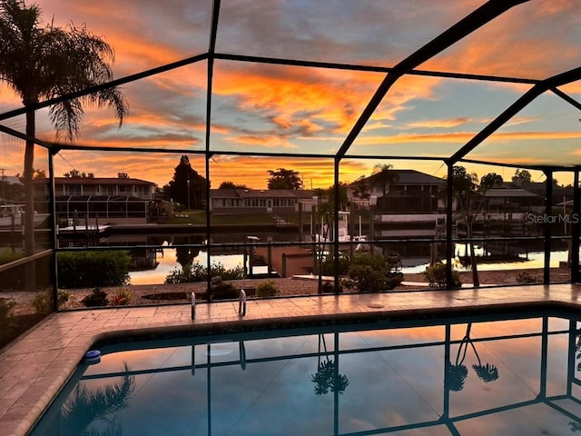 pool at dusk featuring a lanai, a patio area, and an outdoor pool