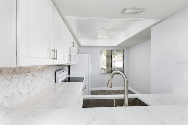 kitchen with light stone countertops, white appliances, visible vents, and a sink