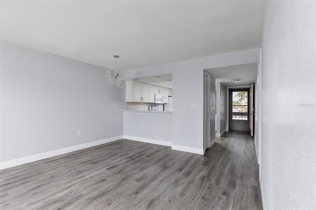 interior space with an inviting chandelier, wood finished floors, and baseboards