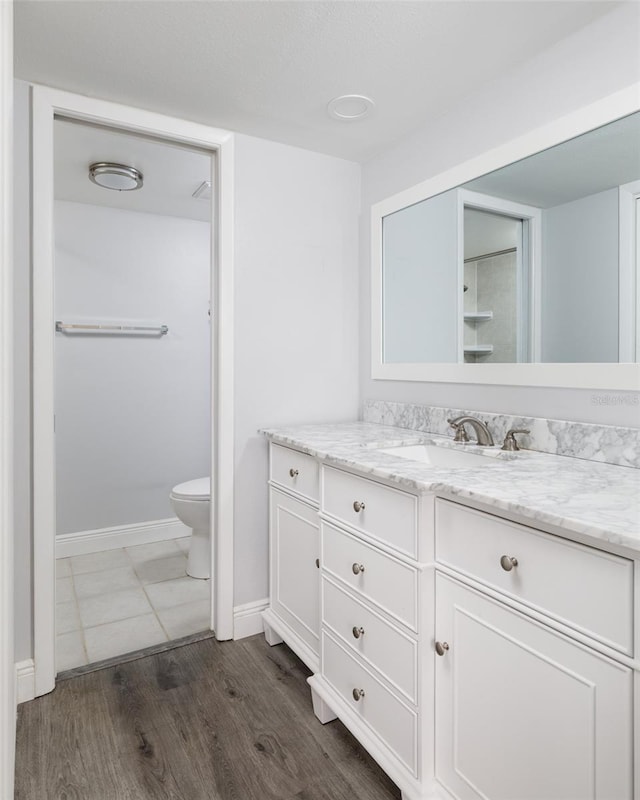 bathroom with toilet, baseboards, wood finished floors, and vanity