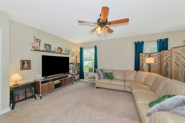 carpeted living area featuring a ceiling fan and baseboards