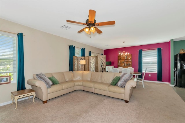 living room featuring carpet, visible vents, baseboards, and ceiling fan with notable chandelier