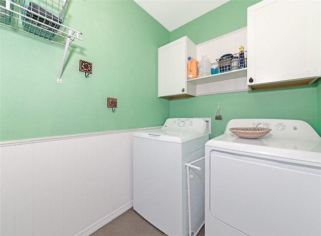 laundry area with wainscoting, washing machine and dryer, and cabinet space