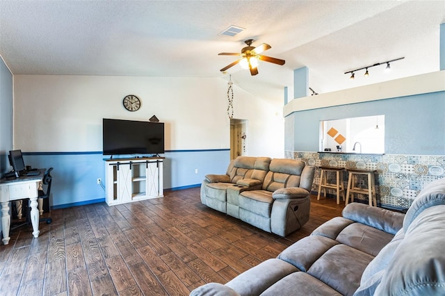 living area with ceiling fan, a textured ceiling, wood finished floors, visible vents, and vaulted ceiling