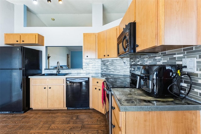 kitchen with black appliances, vaulted ceiling, a sink, and light brown cabinetry