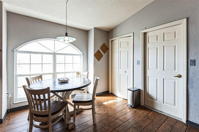 dining area featuring a textured ceiling, vaulted ceiling, dark wood-type flooring, and a textured wall