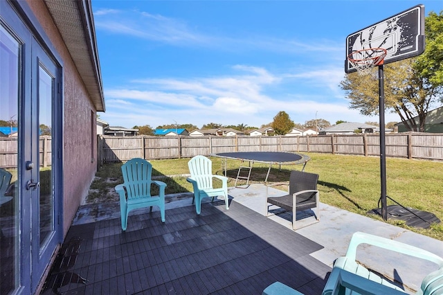 view of patio with french doors, a trampoline, a fenced backyard, and a residential view