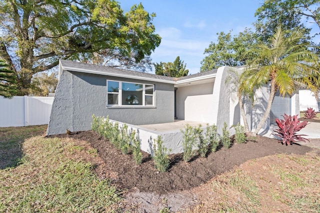 view of front of property with a patio area, fence, and stucco siding