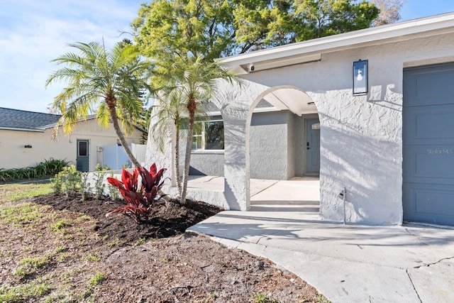 entrance to property featuring a garage and stucco siding