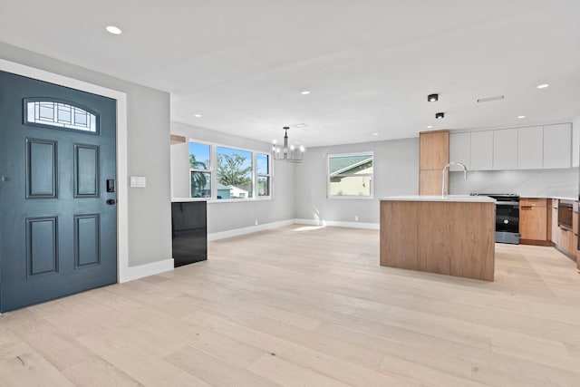 foyer featuring light wood-style flooring, baseboards, a notable chandelier, and recessed lighting