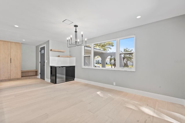 unfurnished living room with light wood-style floors, recessed lighting, a notable chandelier, and baseboards