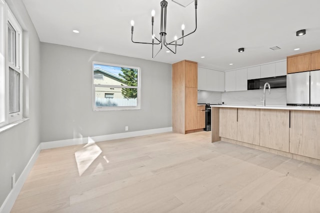 kitchen with freestanding refrigerator, light countertops, light wood-style flooring, and modern cabinets