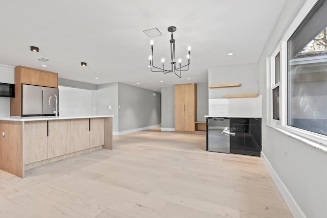 kitchen with black microwave, light countertops, light wood-type flooring, freestanding refrigerator, and modern cabinets