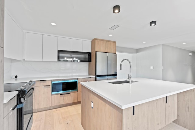 kitchen with a kitchen island with sink, a sink, appliances with stainless steel finishes, light wood-type flooring, and modern cabinets