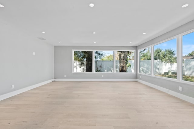 empty room with light wood finished floors, baseboards, and recessed lighting