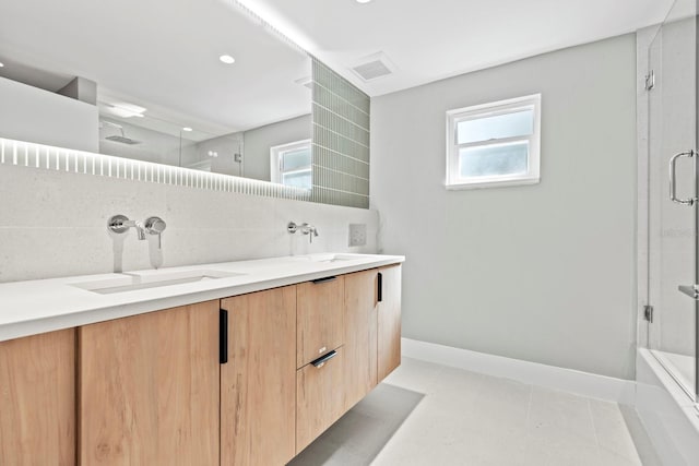 bathroom featuring double vanity, tasteful backsplash, a sink, and baseboards