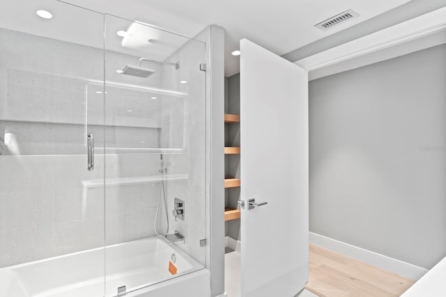 full bath featuring visible vents, shower / bath combination with glass door, baseboards, and wood finished floors