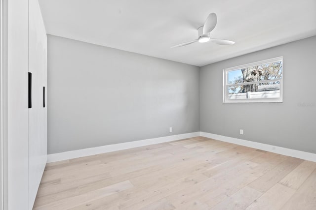 empty room with a ceiling fan, light wood-style floors, and baseboards