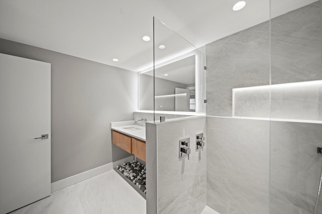 bathroom with recessed lighting, tiled shower, vanity, and baseboards