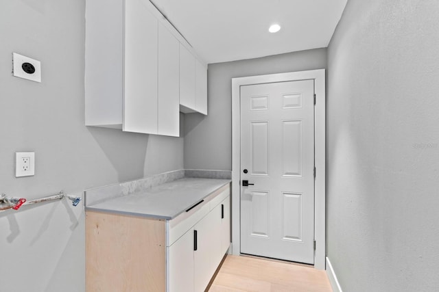 kitchen with light countertops, light wood finished floors, and white cabinets