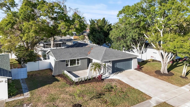 view of front of house with stucco siding, a shingled roof, fence, a garage, and driveway