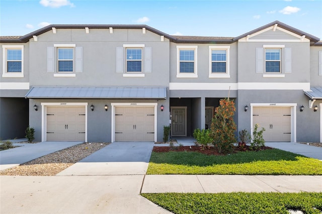 townhome / multi-family property with a standing seam roof, metal roof, concrete driveway, and stucco siding