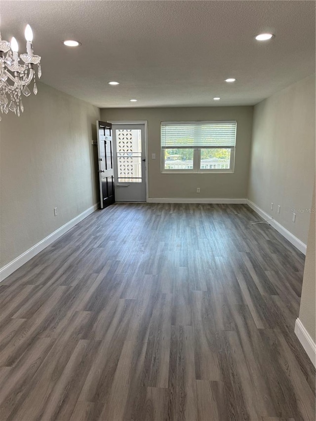 spare room with dark wood-style flooring, a textured ceiling, and baseboards