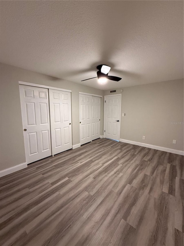 1000 49th St N Unit 309, Saint Petersburg, FL 33710 - unfurnished bedroom featuring multiple closets, dark wood finished floors, and baseboards