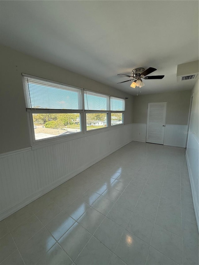 1000 49th St N Unit 309, Saint Petersburg, FL 33710 - spare room with a wainscoted wall, light tile patterned flooring, visible vents, and a ceiling fan
