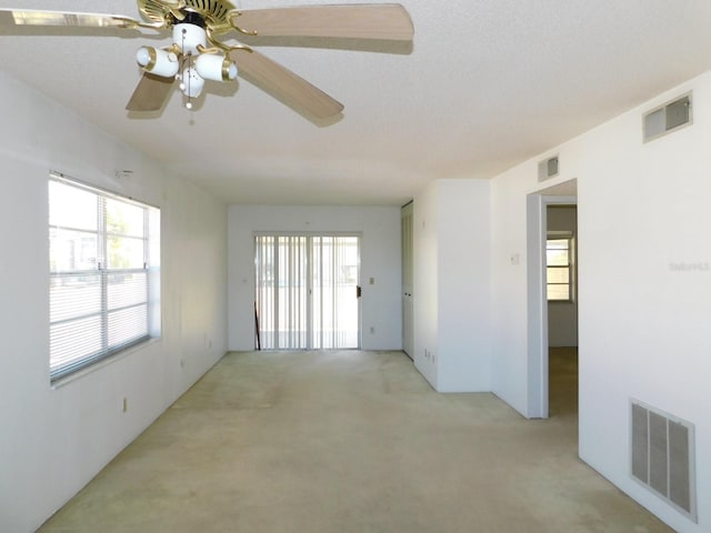 spare room featuring visible vents, ceiling fan, and light carpet