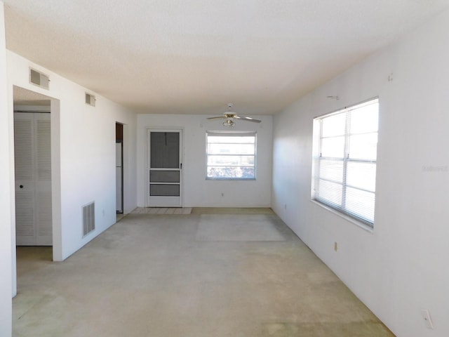 unfurnished room featuring a ceiling fan, visible vents, and concrete floors