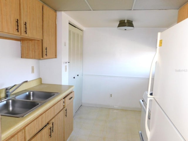 kitchen featuring light countertops, light floors, a sink, and freestanding refrigerator